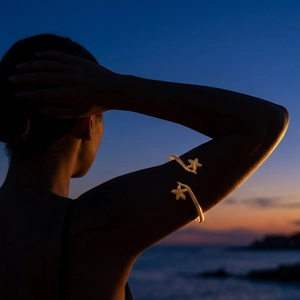 Golden starfish arm cuff bracelet with bohemian design worn by model at sunset beach