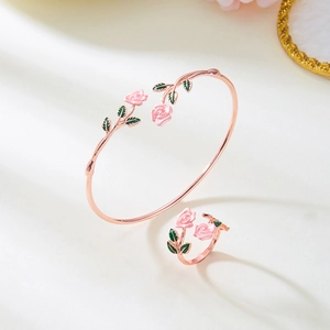 Detail van roségouden bloem sieradenset met roze emaille bloemblaadjes en groene bladeren