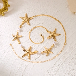 Détail de la chaîne de corps étoile de mer dorée avec perles blanches sur fond texturé