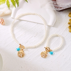 Detail of pearl jewelry set with blue starfish and golden shell charms on OT clasp