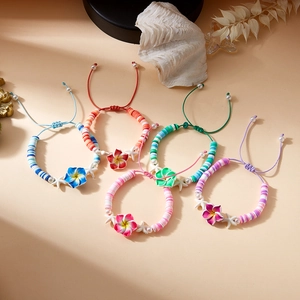 Detail of colorful bohemian plumeria flower and starfish beaded bracelets on warm sand