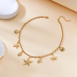 Close-up of gold sea shell necklace featuring small starfish charms and lobster clasp