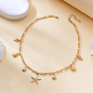 Detail of gold starfish and shell charms on layered necklaces with pearl accents