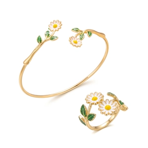 Detail van gouden madeliefje armband en ring set met wit emaille en groene bladeren