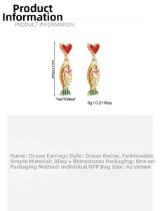 Detail view of gold alloy fish earrings with red heart and crystals showing size dimensions