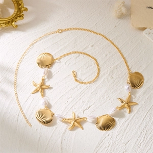 Détail de chaîne de taille dorée avec pendentifs étoiles de mer coquillages et perles