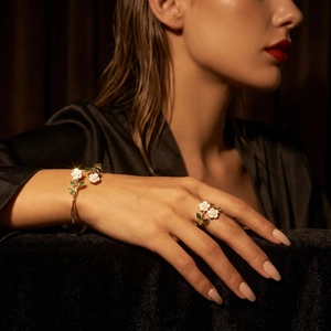 Detail van de wit geëmailleerde rozenbloem armband en ring set op bruine fluwelen achtergrond