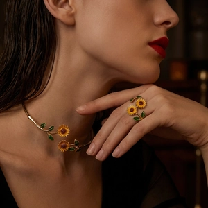Macro-opname van vergulde zonnebloem halsband en open ring met kleurrijk emaille detail