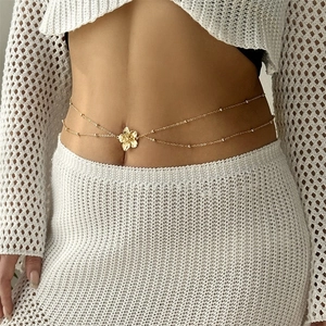 Chaîne de taille dorée chic avec pendentif fleur sur un mannequin en vêtements blancs