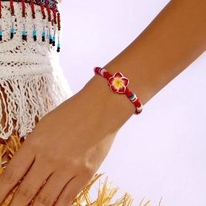 Detail of a red tropical plumeria clay bead bracelet on a bohemian style model