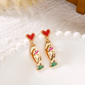 Detail view of heart-shaped studs and textured golden fish earrings on a white ceramic plate