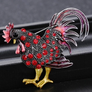 Vue macro d'une broche coq avec des strass rouges et des ailes en émail dégradé brillant