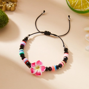 Detail of handmade plumeria flower bracelet with colorful clay beads and adjustable cord