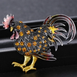 Détail macro d'une broche coq vintage avec des strass orange vifs et des motifs gravés