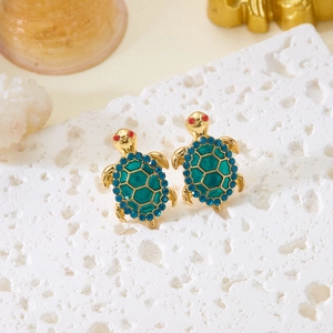 Macro detail of gold sea turtle earrings with green enamel and blue crystals inlay