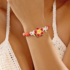 Close-up of beach bracelet with frangipani flower, starfishes and pearls worn on wrist