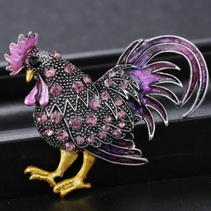 Détail macro d'une broche coq en alliage avec strass violets et artisanat émaillé