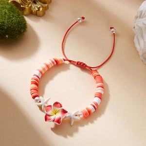 Detail of tropical frangipani flower and starfish charms on clay bead bracelet