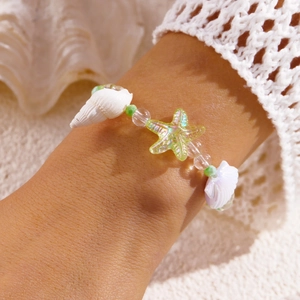 Detailaufnahme eines Meeres-Perlenarmbands mit grünem Seestern und weißer Meeresmuschel