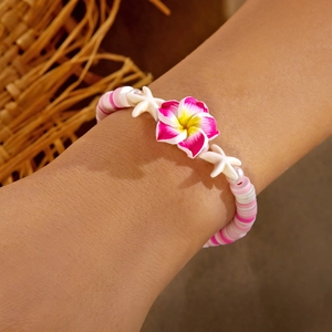 Detail of summer style handmade beaded bracelet with pink plumeria and starfish charms