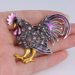 Détail d'une broche coq faite main avec émail violet et strass roses brillants