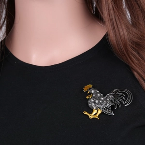 Gros plan d'une broche coq faite main avec cristaux sur le revers d'un blazer noir