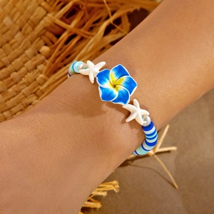 Detail of beach style beaded bracelet with blue plumeria flower and white starfish