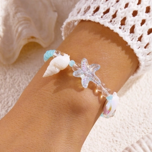 Detail eines blauen Perlenarmbands mit schillerndem Seestern und Muschelanhänger
