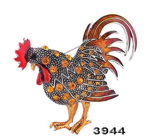 Vue détaillée d'une broche coq faite main avec des strass ambrés et de l'émail rouge vif