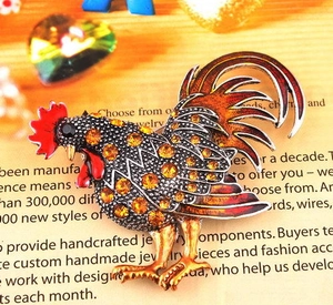 Vue détaillée d'une broche coq vibrante avec strass colorés sur une base en métal doré