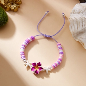 Detail of colorful plumeria flower and starfish charms on a purple beaded cord bracelet