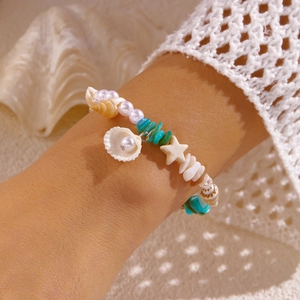 Detail eines Strandarmbands mit Seestern-Anhängern, blauen Steinen und Meeresmuschel