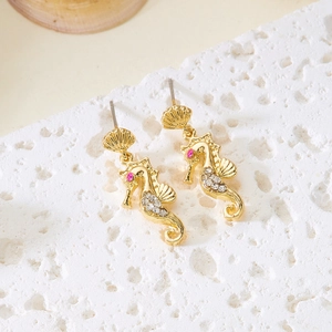 Detail view of golden seahorse earring with pink stones and shell on coral stand