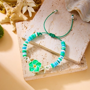 Detail of colorful plumeria flower and heishi beads on a beach-style woven bracelet