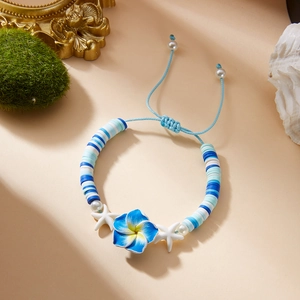 Detail of blue clay flower bracelet with starfish and pearls on a beach style backdrop
