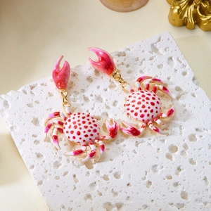 Detail of crab earrings with pink polka dots and gold accents on stone display