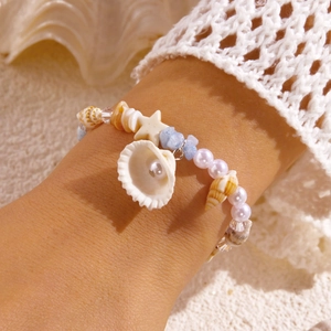 Detail eines Strandarmbands mit Muscheln, Türkissteinen und einem kleinen Seestern-Anhänger