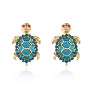 Detailed macro view of gold turtle earrings with blue crystal shells and red zircon eyes