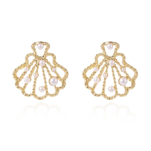 Detailed macro view of golden shell earrings with white pearl accents and hollow design