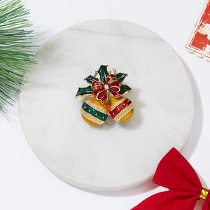 Detail einer Weihnachtsglocken-Brosche mit roter Schleife, Stechpalme und funkelnden Strass