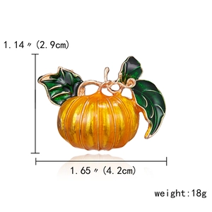 Vibrant orange enamel pumpkin brooch with green leaves and gold trim for Halloween style