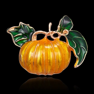 Macro detail of pumpkin brooch featuring orange enamel texture and golden metal lines