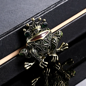Retro frog prince brooch with crown and green gemstone on a black leather box