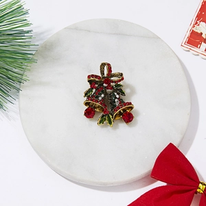 Makrodetail der Weihnachtsglocken-Brosche mit roten Steinen auf Marmorhintergrund