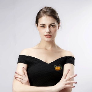 Close-up of bright orange pumpkin brooch with green leaf on a black dress lapel