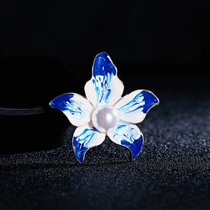 Detailansicht von blauen Emaille-Blütenblättern mit einer großen weißen Perle in der Mitte