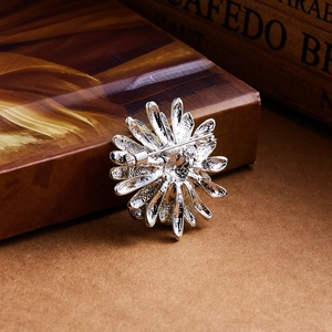 Close-up detail of silver sunflower brooch back with metal texture and safety pin clasp