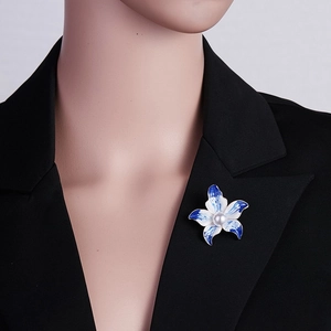 Detail einer eleganten blauen Blumen-Perlenbrosche an einem schwarzen Anzug-Kragen