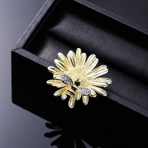 Macro detail of enamel sunflower brooch featuring a rhinestone honey bee on a jewelry box