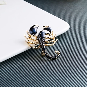 Close-up of golden scorpion brooch with deep blue enamel details and polished metal